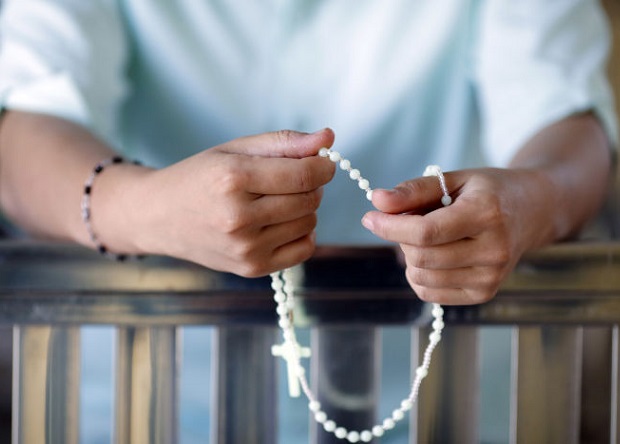 Young catholic woman praying the rosary beads.   Vietnam.